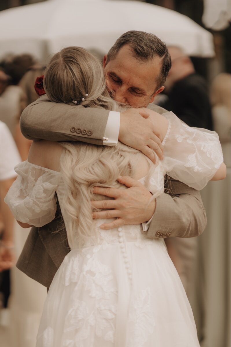 Hochzeitsportfolio, Brautvater umarmt die Braut innig bei den Glückwünschen nach der Trauung