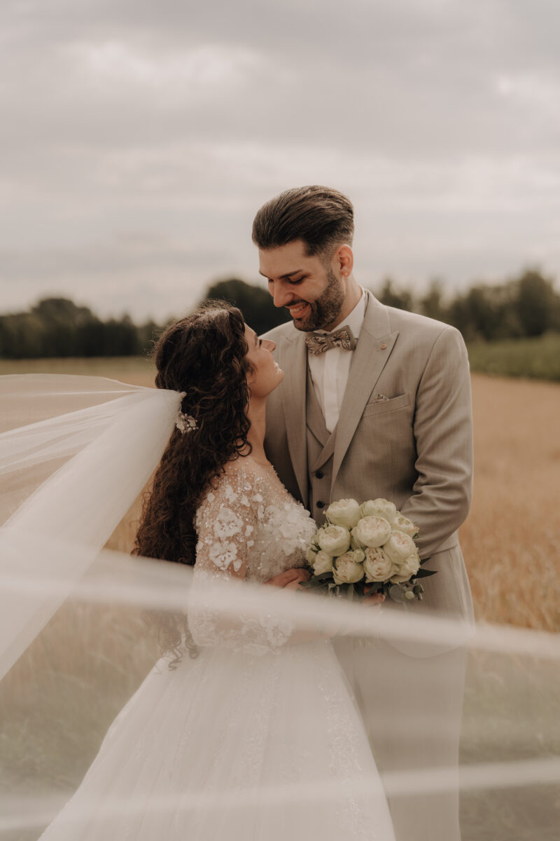 Hochzeitsportfolio, Brautpaarshooting im Feld mit Schleier im Wind | Hochzeitsfotografie NRW