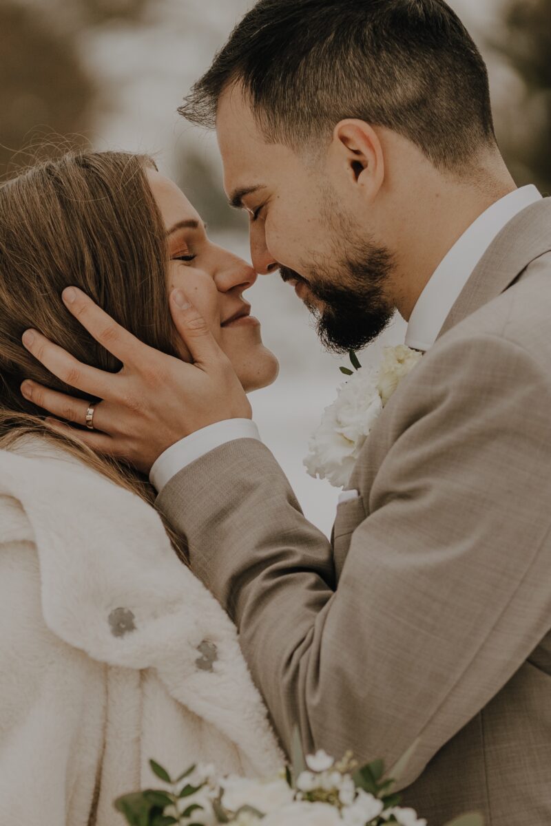 After Wedding, Nahaufnahme, die Nasenspitzen der Braut und des Bräutigams berühren sich. Er hält ihr Gesicht in den Händen.