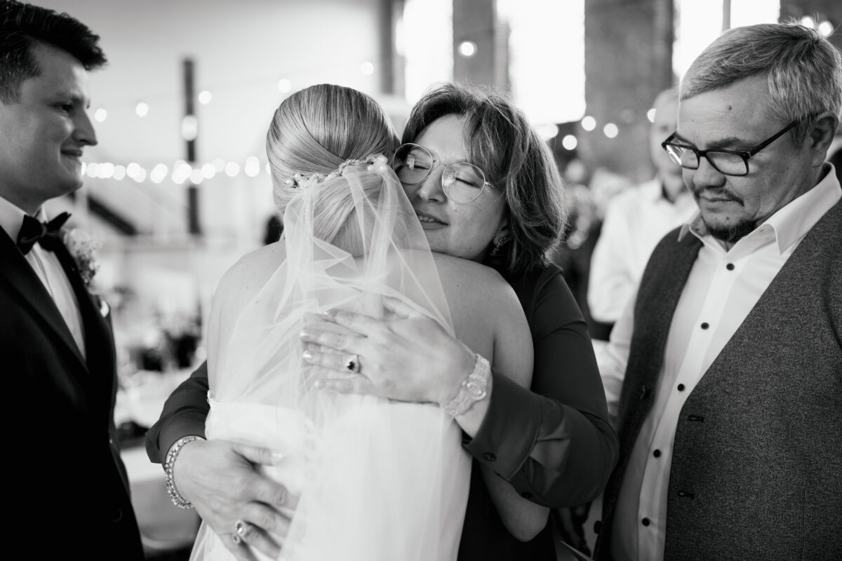 Hochzeitsportfolio, emotionaler Moment zwischen Braut und Familie während den Glückwünschen, Mutter umarmt die Braut innig | Hochzeitsreportage NRW
