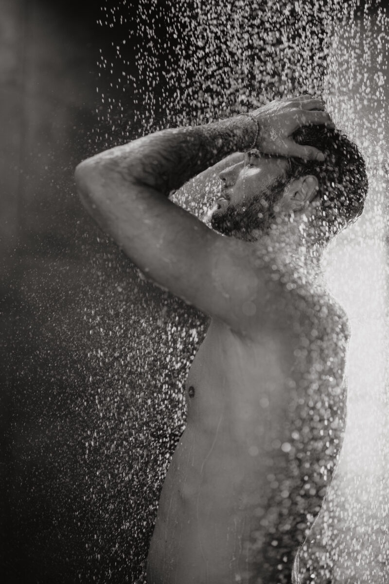 Akt- und Erotikfotografie Portfolio, oberkörperfreier Mann unter Regendusche, schwarz-weiß