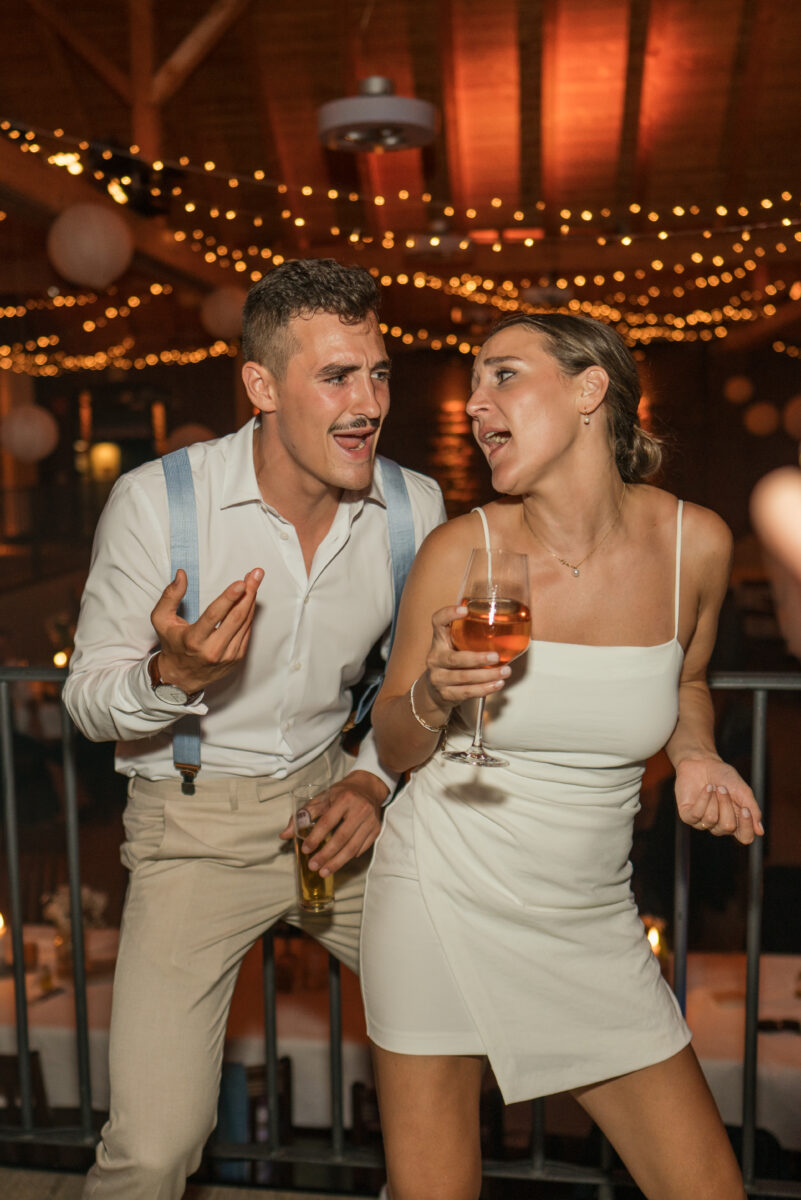 Hochzeitsportfolio, Frau mit einem Aperol in der Hnd am tanzen und der Mann neben ihr tanzt ebenfall udn hat ein Kölschglas in der Hand, die Gesichter sind zueinander gewandt und sind am singen