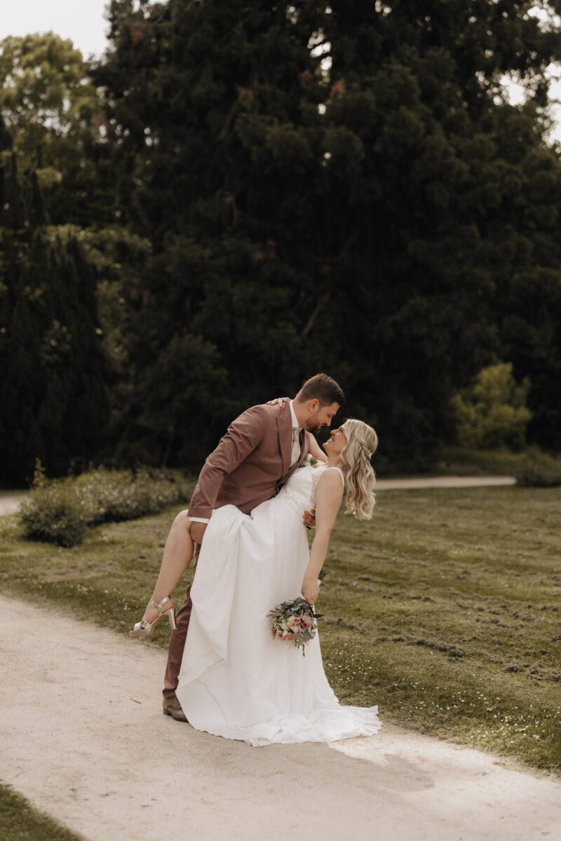 Hochzeitsportfolio, Romantischer Hochzeitsmoment – Bräutigam hebt das eine Bein der Braut an und lässt sie nach hinten lehnen beim Paarshooting | Hochzeitsfotografie NRW