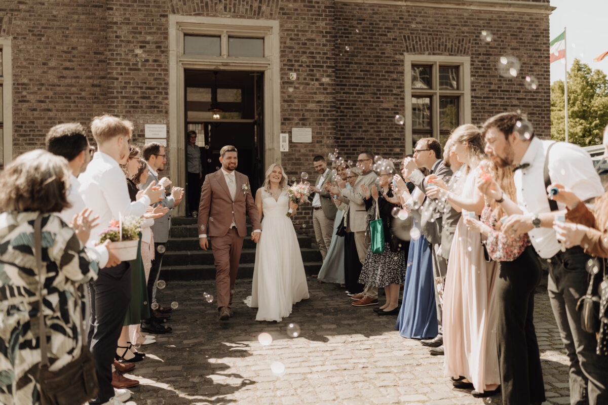 Hochzeitsportfolio, Brautpaar läuft durch ein Spalier aus Hochzeitsgästen nach der Trauung | Hochzeitsfotografie NRW