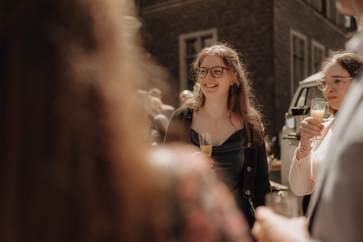 Hochzeitsportfolio, Portrait von einer Frau, sie hat ein Sektglas in der Hand und lächelt eine Person an