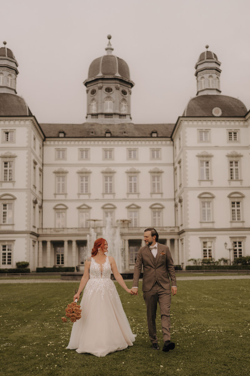 Hochzeitsportfolio, Hochzeitspaar vor dem Schloss Bensberg, läuft auf die Kamera zu