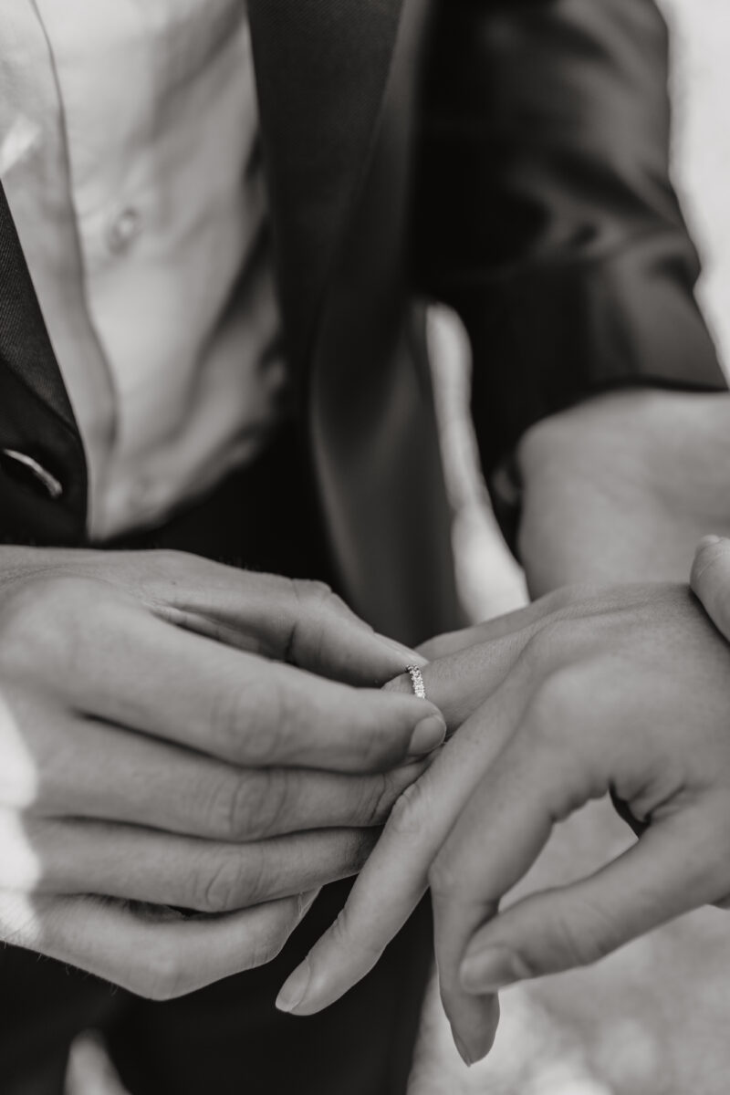 Detailfoto, wie der Brätigam der Braut den Ring an die Hand steckt