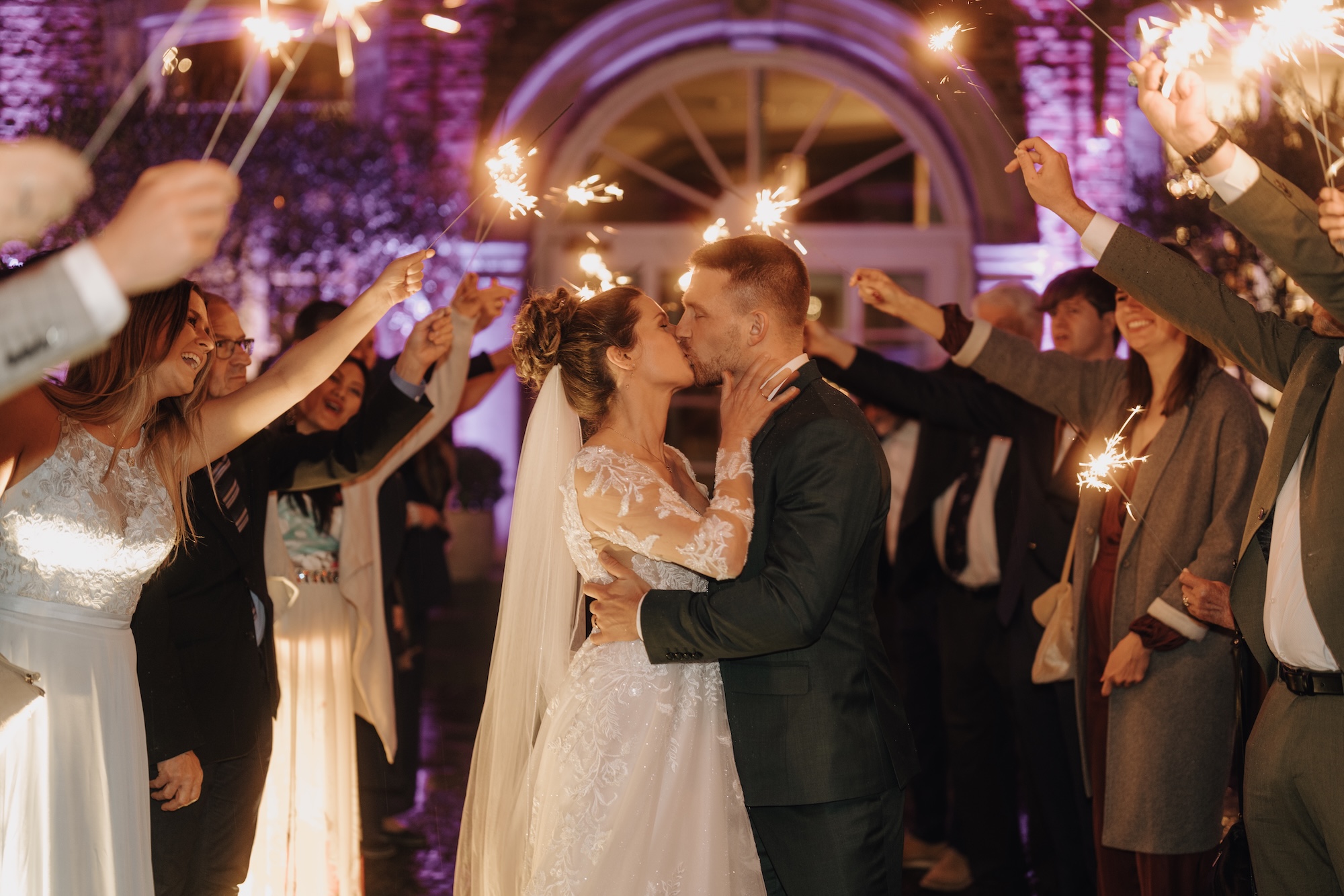 Hochzeitspaar küsst sich bei der Hochzeitsfeier vor Gästen mit Wunderkerzen. - Wolkenburg Köln Hochzeit 